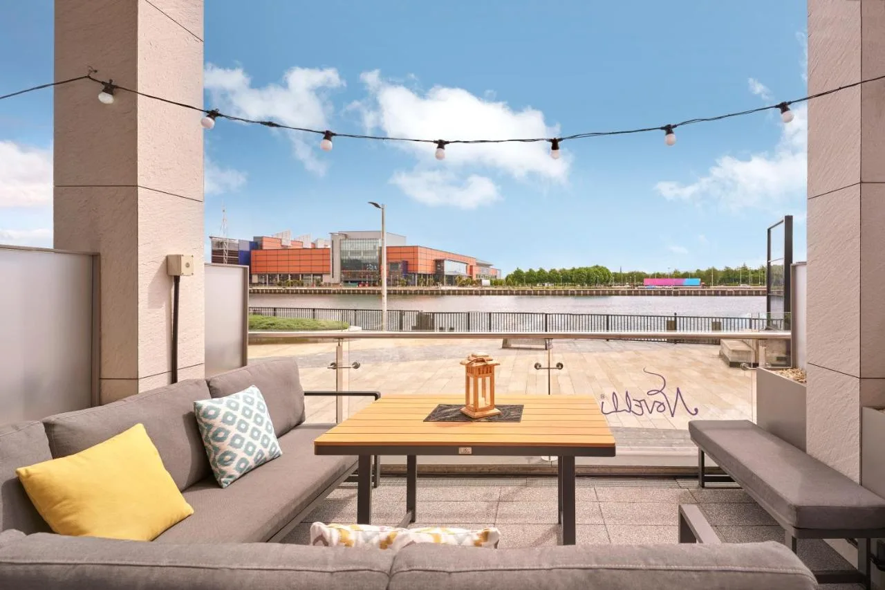 a patio with a couch and a table on a balcony at AC Hotel by Marriott Belfast in Belfast
